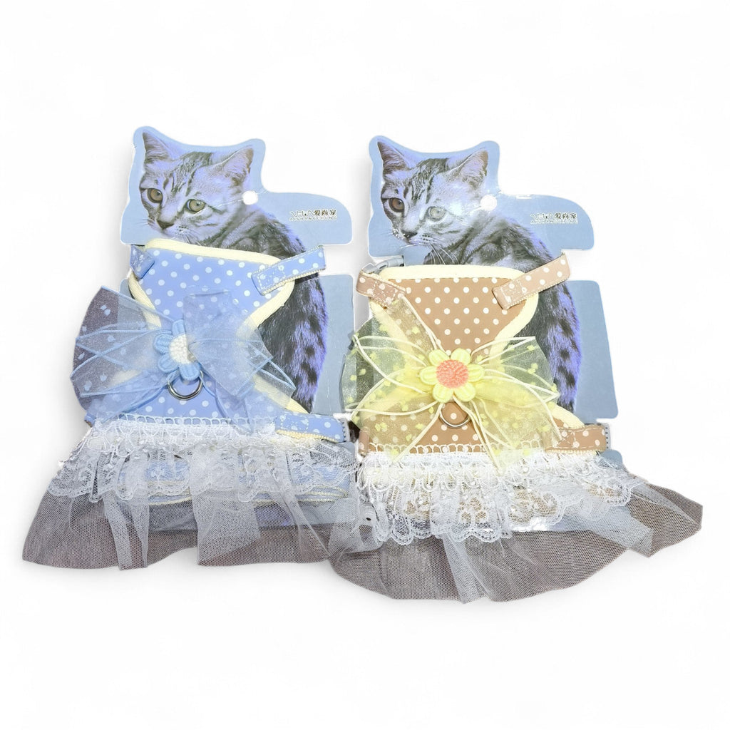 Two decorative cat harnesses from maroc-animalerie: one blue with white polka dots and a blue bow, the other brown with white polka dots and a yellow bow. Both feature lace trim and a floral accent.