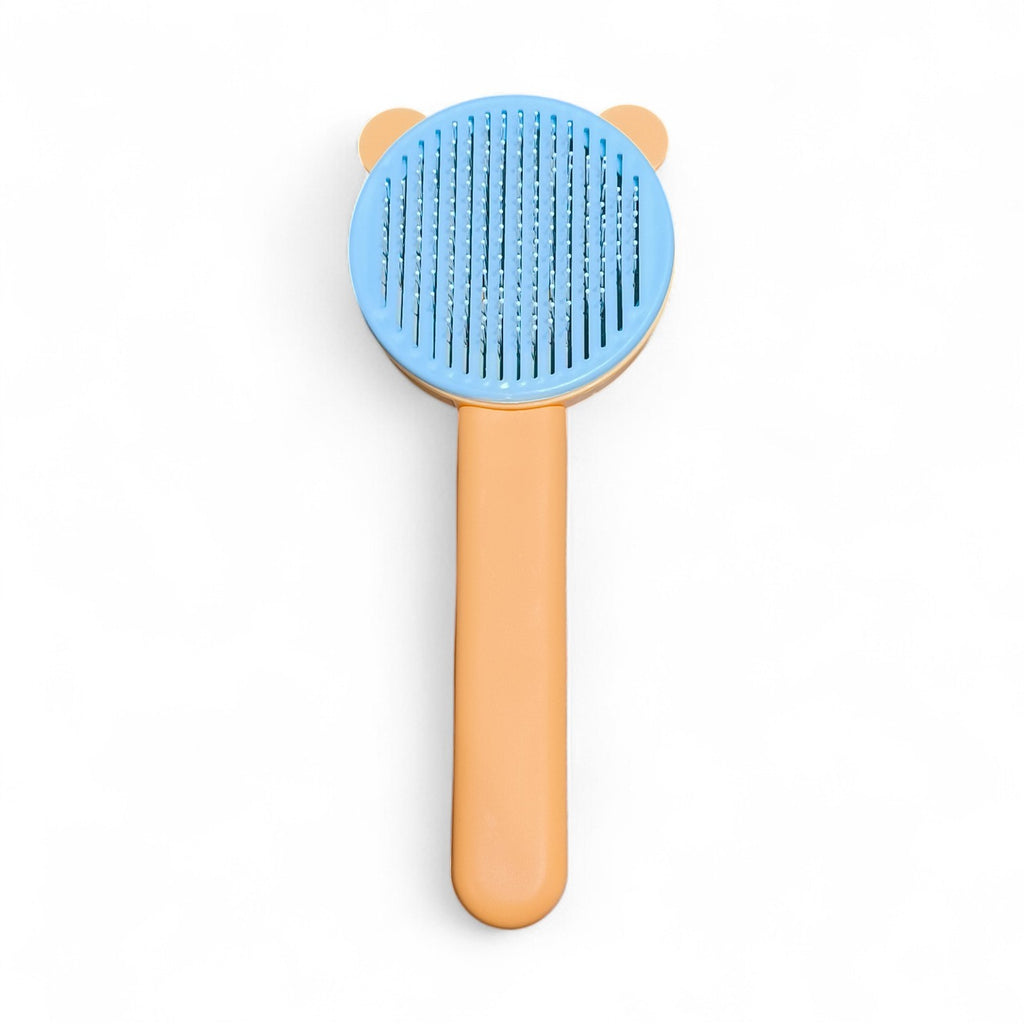 Maroc-animalerie self-cleaning pet grooming brush with blue bristles and orange handle, featuring a cute bear design.